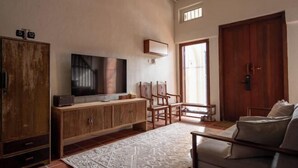A living room with a television, wooden furniture, a patterned rug, and a large wooden door. - Lumut Heritage - a walk to Armenian St Art & Cafes (George Town)