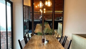 Una mesa de comedor de madera con sillas, un florero y una planta en maceta.