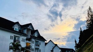 Una hilera de edificios blancos de varios pisos con balcones, frente a un cielo nublado.