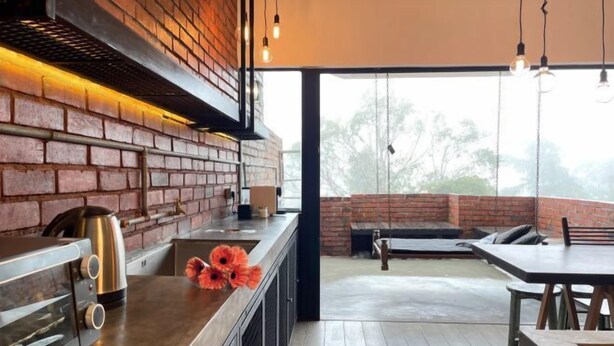 Una cocina moderna con pared de ladrillo, un tostador de acero inoxidable y una cafetera.