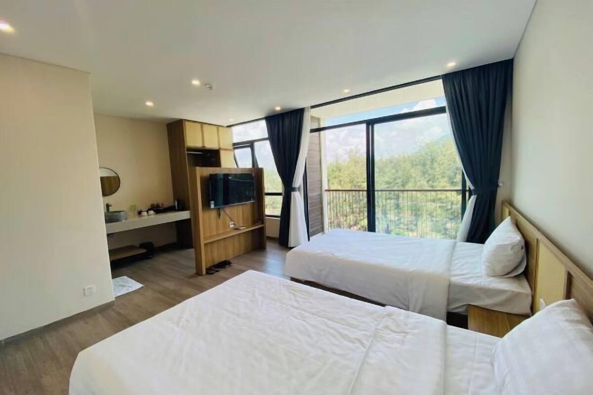 Une chambre d’hôtel avec deux lits, une télévision, un bureau et un balcon avec vue.
