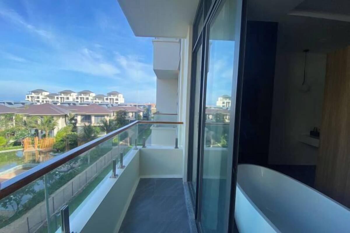Un balcon doté d’une balustrade en verre donnant sur un quartier résidentiel.