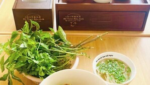 A wooden tray with a box labeled "Aurora" and a bowl of soup with green herbs. - Aurora Bao Anh Hotel (Binh Kien)