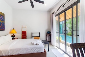 A bedroom with a bed, a nightstand, a lamp, a chair, and a view of a swimming pool.