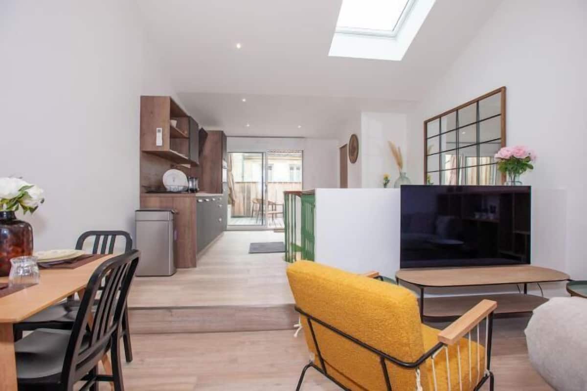 A modern living space with a dining area, kitchen, and a TV.