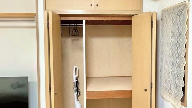 Ein Holfschrank mit geöffneten Türen, der Regale und Kleiderstangen zeigt.