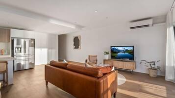 A modern living room with a brown leather sofa, a flat-screen TV, and a wooden cabinet.