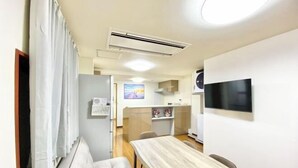 Une pièce moderne comprenant une table à manger, un canapé, un téléviseur et un coin cuisine.