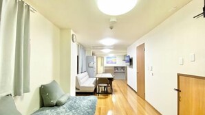 Une chambre d’hôtel de taille réduite comprenant un lit, un petit canapé, un coin repas et une kitchenette.
