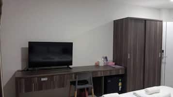 A hotel room with a bed, a TV, a desk, a wardrobe, and a small seating area.