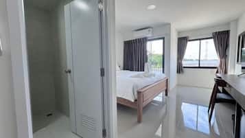 Une chambre d’hôtel avec un lit, un bureau, une chaise et une vue sur l’extérieur.