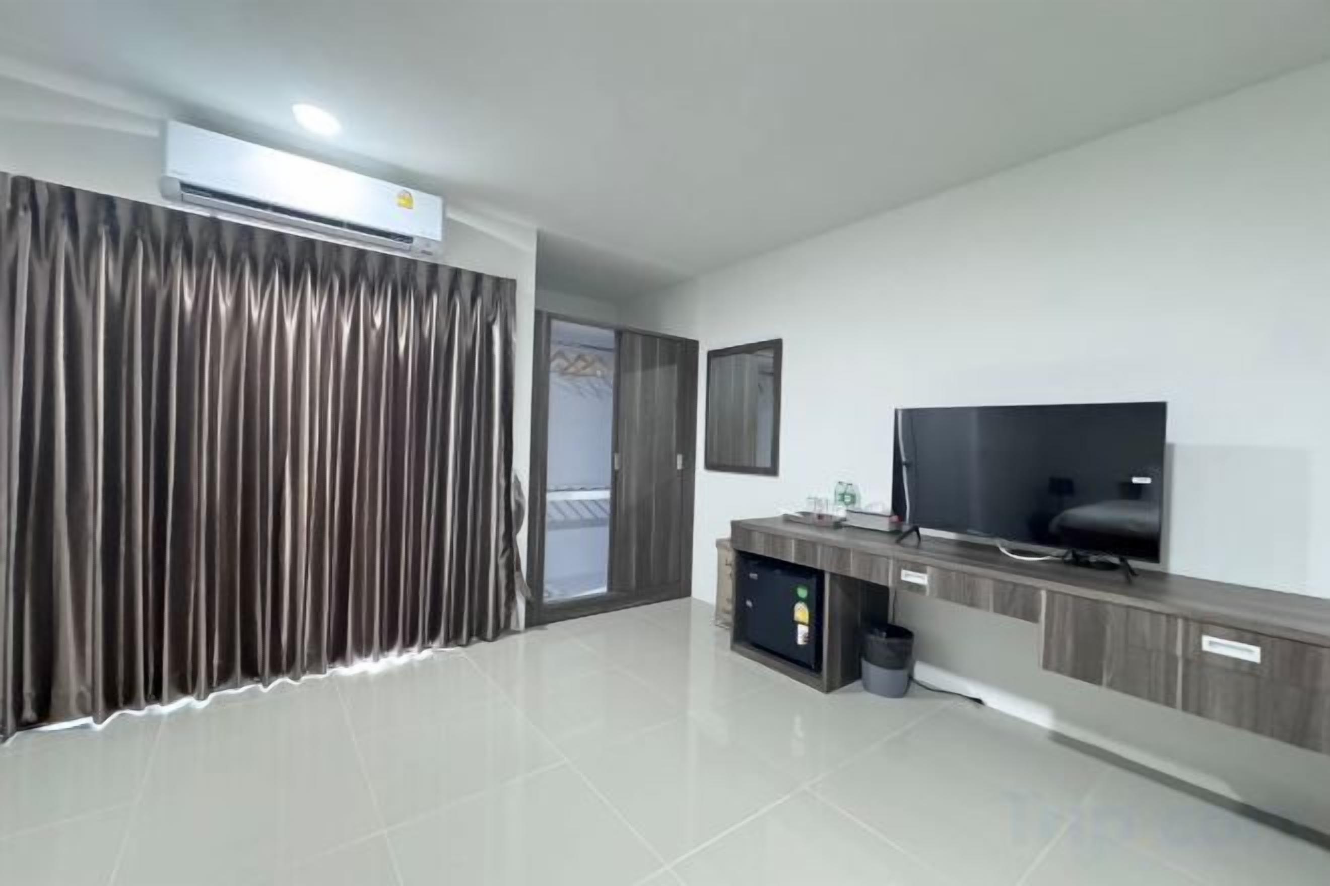 Une chambre d’hôtel moderne dotée d’une télévision à écran plat, d’un minibar et d’une grande fenêtre avec des rideaux.