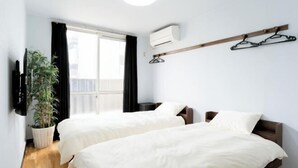A room with two beds, a potted plant, a TV, and a window with curtains. - Sparrow Color · Fangnan (Tokyo)
