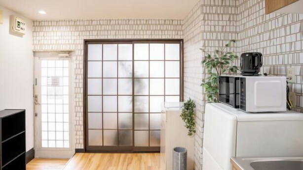 A compact kitchen with a microwave, a sink, and a sliding door leading to a balcony. - Sparrow Color · Fangnan (Tokyo)
