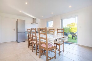 A dining area with a table and chairs, a refrigerator, and a sliding glass door leading to an outdoor area.