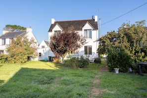 A residential house with a well-maintained lawn, a pathway leading to the front door, and a clear sky.