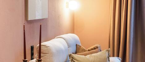 A cozy room with a sofa, a dining table with chairs, a wooden bowl, and a wall-mounted light fixture.