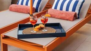 A rooftop lounge with two sunbeds, a tray with drinks and oranges, and a city view. - LOS 36 BY GRUPO CCOMMO (Murcia)