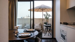 A dining area with a table set for two, a chair, a small table with a plant, and a large umbrella. - LOS 36 BY GRUPO CCOMMO (Murcia)