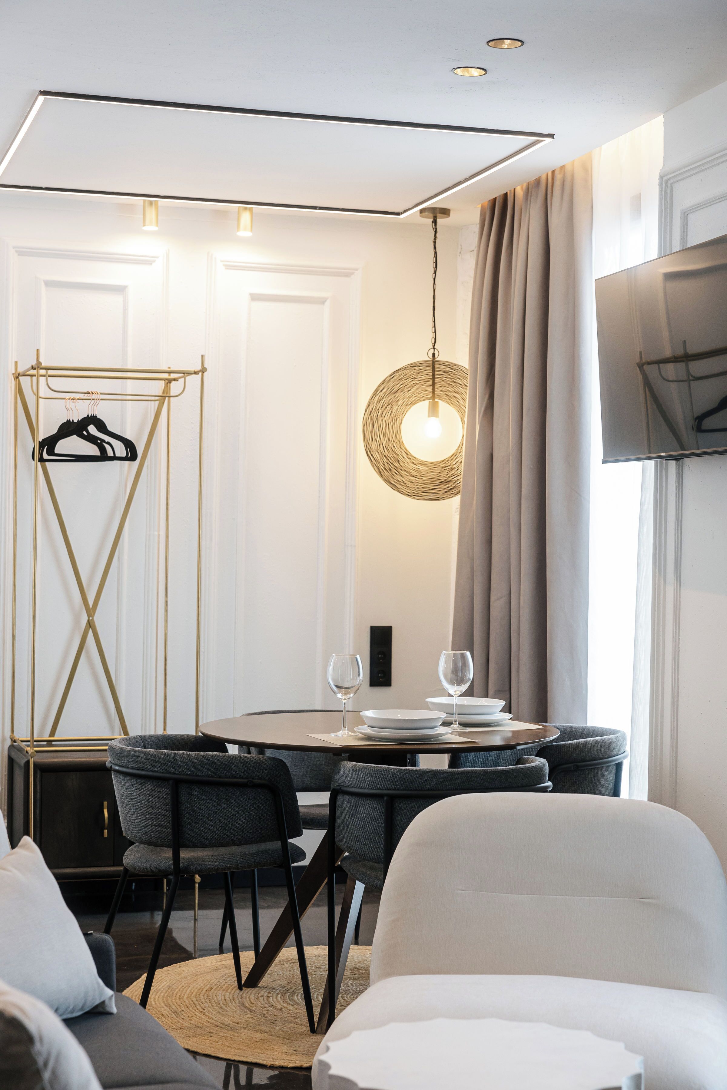 Un área de comedor moderna con una mesa redonda, sillas y una lámpara colgante.
