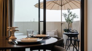A dining area with a table set for two, an umbrella, and a view of the cityscape through large windows. - LOS 36 BY GRUPO CCOMMO (Murcia)