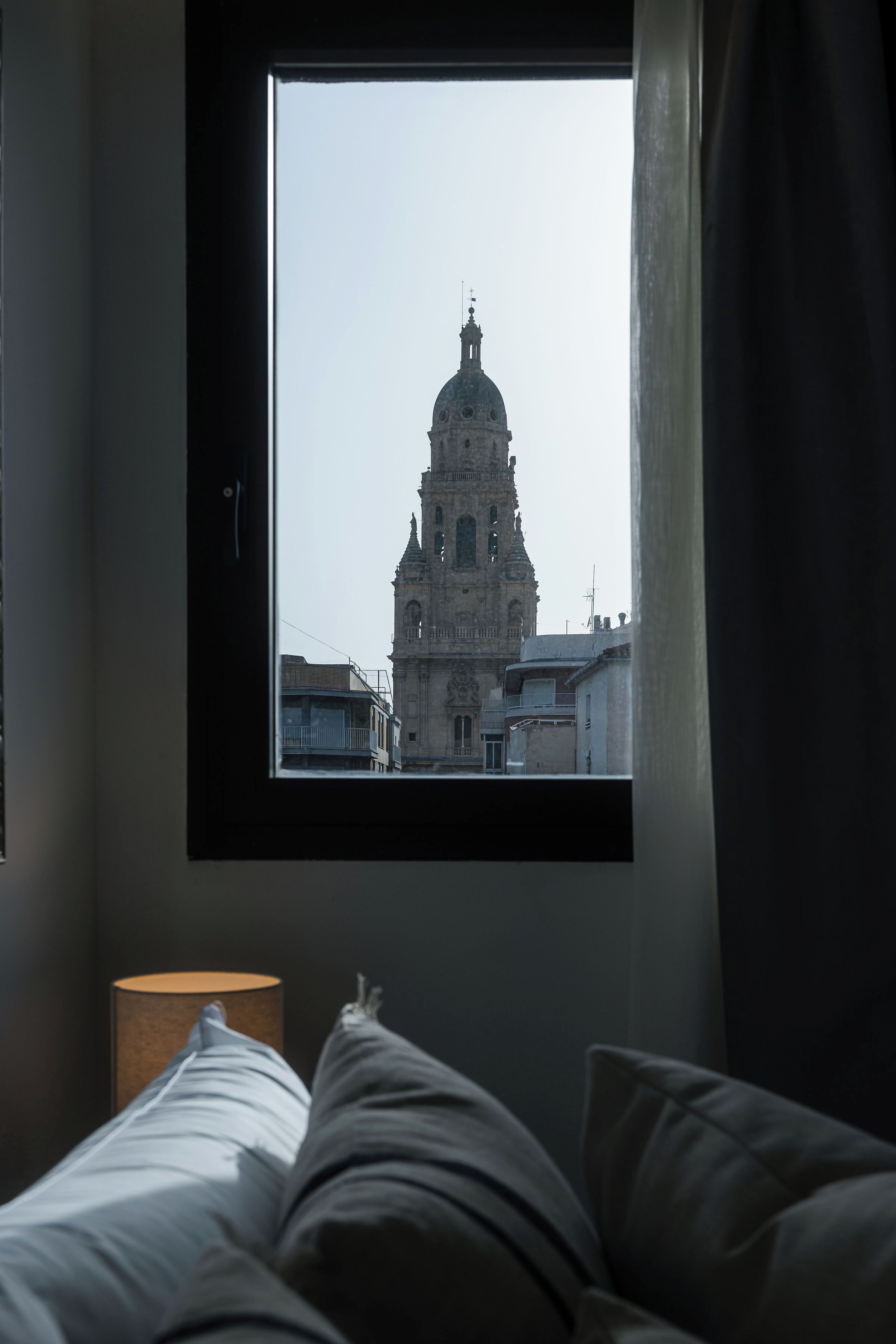 Ein Zimmer mit einem Bett, einem Fenster und einer Lampe.