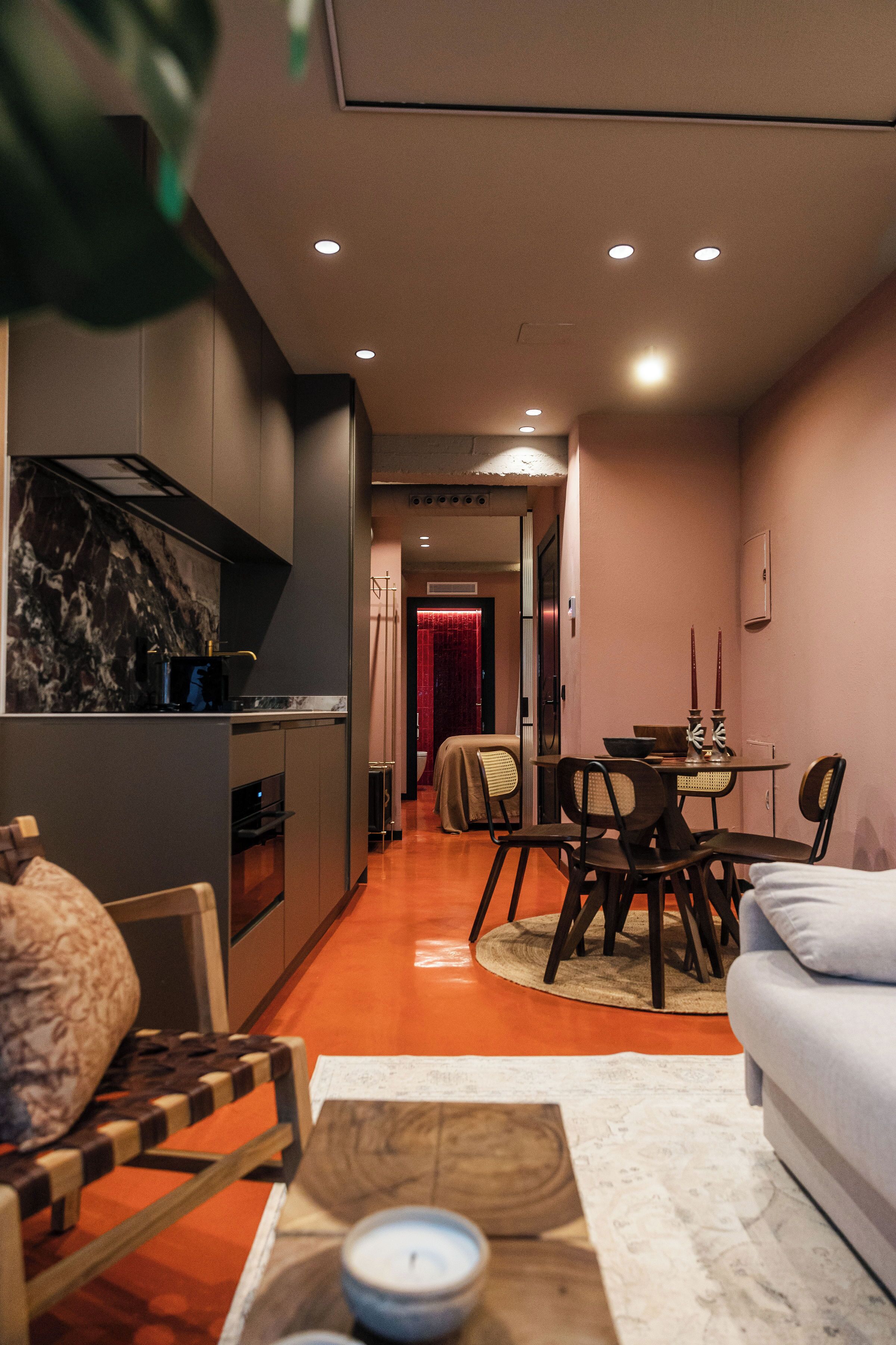 A modern kitchen with a marble backsplash, a dining area with a table and chairs, and a living room with a sofa.