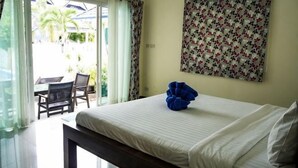 Een slaapkamer met een bed, een bankje, een stoel, een raam met gordijnen en een bloemenpatroon op de muur.