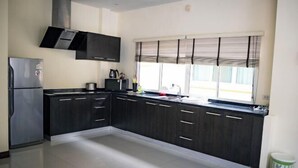 Een moderne keuken met donkere kastjes, een koelkast van roestvrij staal en een raam met zonwering.