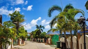 Een woonstraat met huizen, palmbomen en een helderblauwe lucht.
