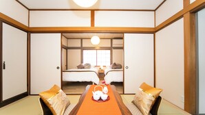 A traditional Japanese room with tatami flooring, two beds, a wooden table with a tray of tea sets, and a sliding door leading to another room. - Yokkaichi Kawaramachi Hotel (Yokkaichi)