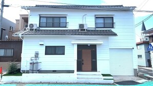 A two-story white building with a brown door, air conditioning units, and a small porch. - Yokkaichi Kawaramachi Hotel (Yokkaichi)