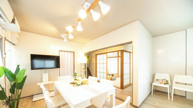 A modern living room with a white dining table, chairs, a flat-screen TV, and a large window. - Yokkaichi Kawaramachi Hotel (Yokkaichi)