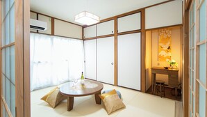 A traditional Japanese room with tatami flooring, a round table with a bottle and glasses, and sliding doors. - Yokkaichi Kawaramachi Hotel (Yokkaichi)