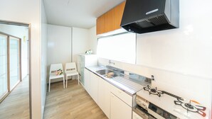 A modern kitchen with white cabinets, a stainless steel sink, and a black range hood. - Yokkaichi Kawaramachi Hotel (Yokkaichi)