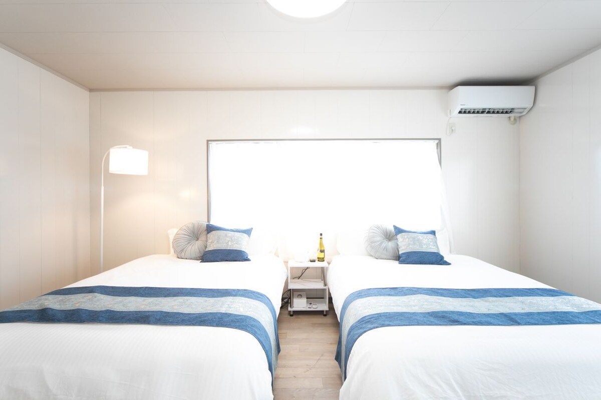 Een hotelkamer met twee bedden, een nachtkastje, een lamp en een airconditioner.