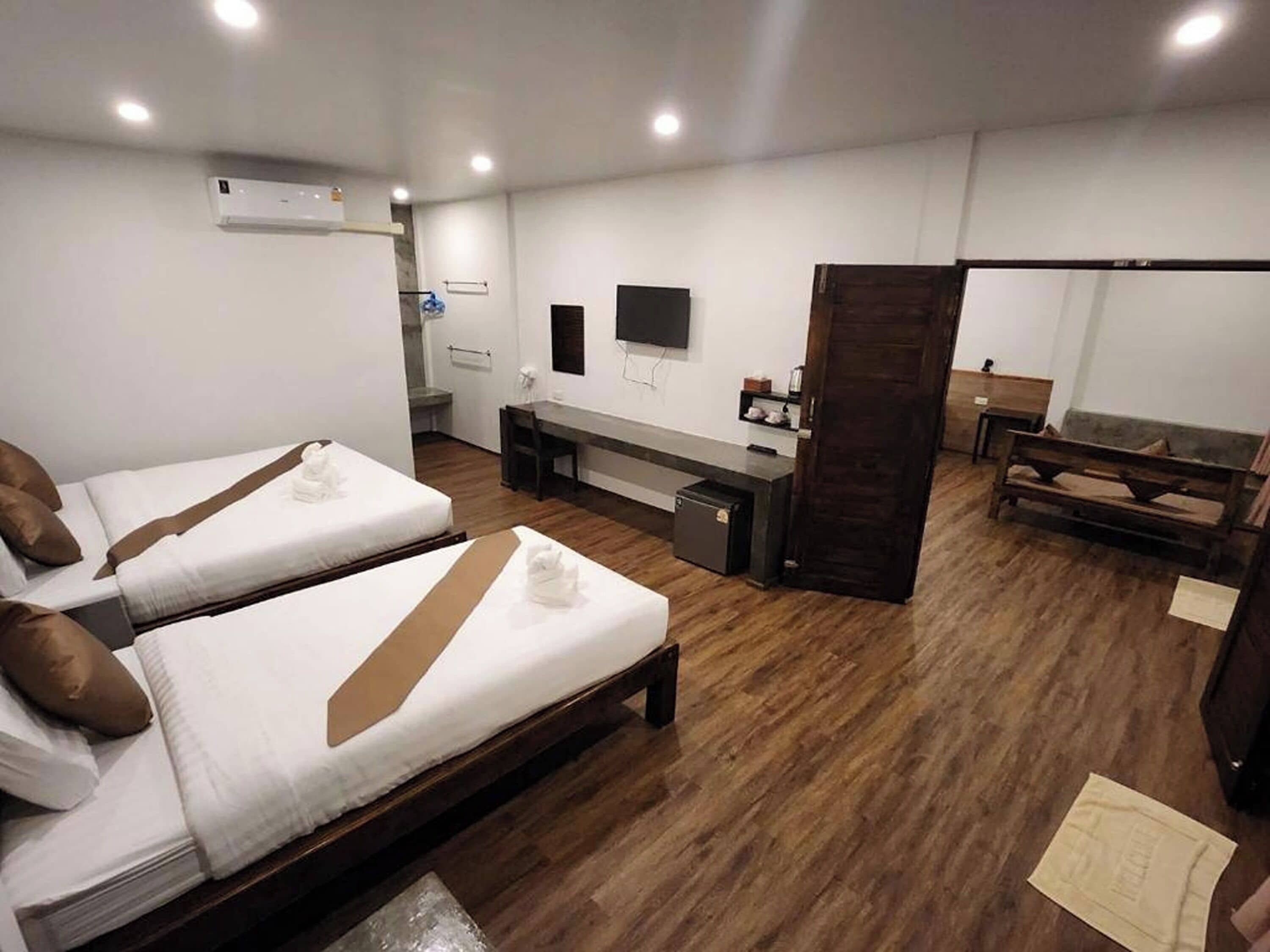 Une chambre d’hôtel avec deux lits, un bureau, une télévision et un plancher en bois.