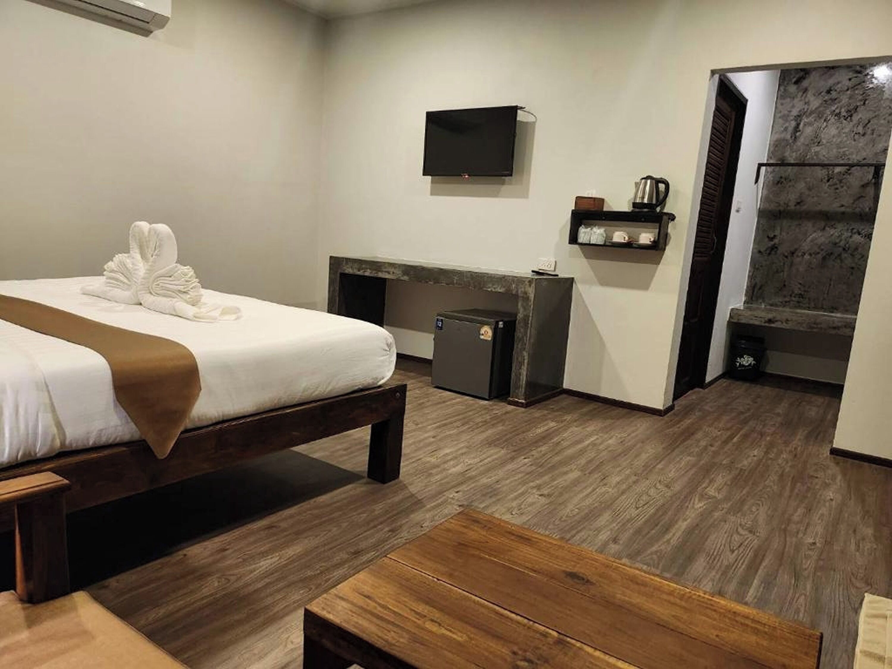 A hotel room with a bed, a desk, a TV, and a small seating area.