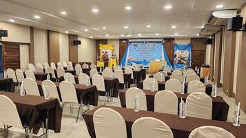 A conference room with rows of tables and chairs, a stage with a banner, and a podium.