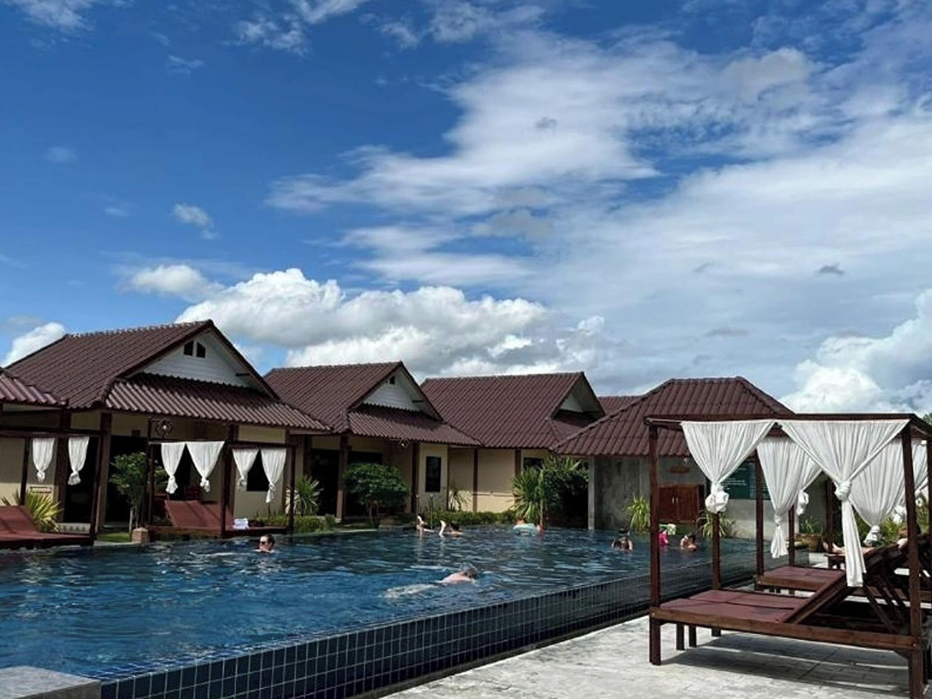 A pool area with multiple lounge chairs and umbrellas, surrounded by buildings with a consistent architectural style.