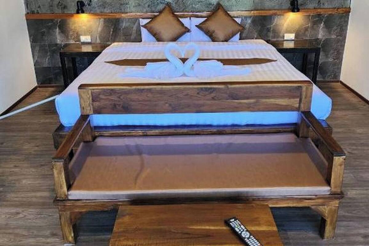Una cama con estructura de madera, un colchón azul y una decoración con forma de corazón en la colcha.
