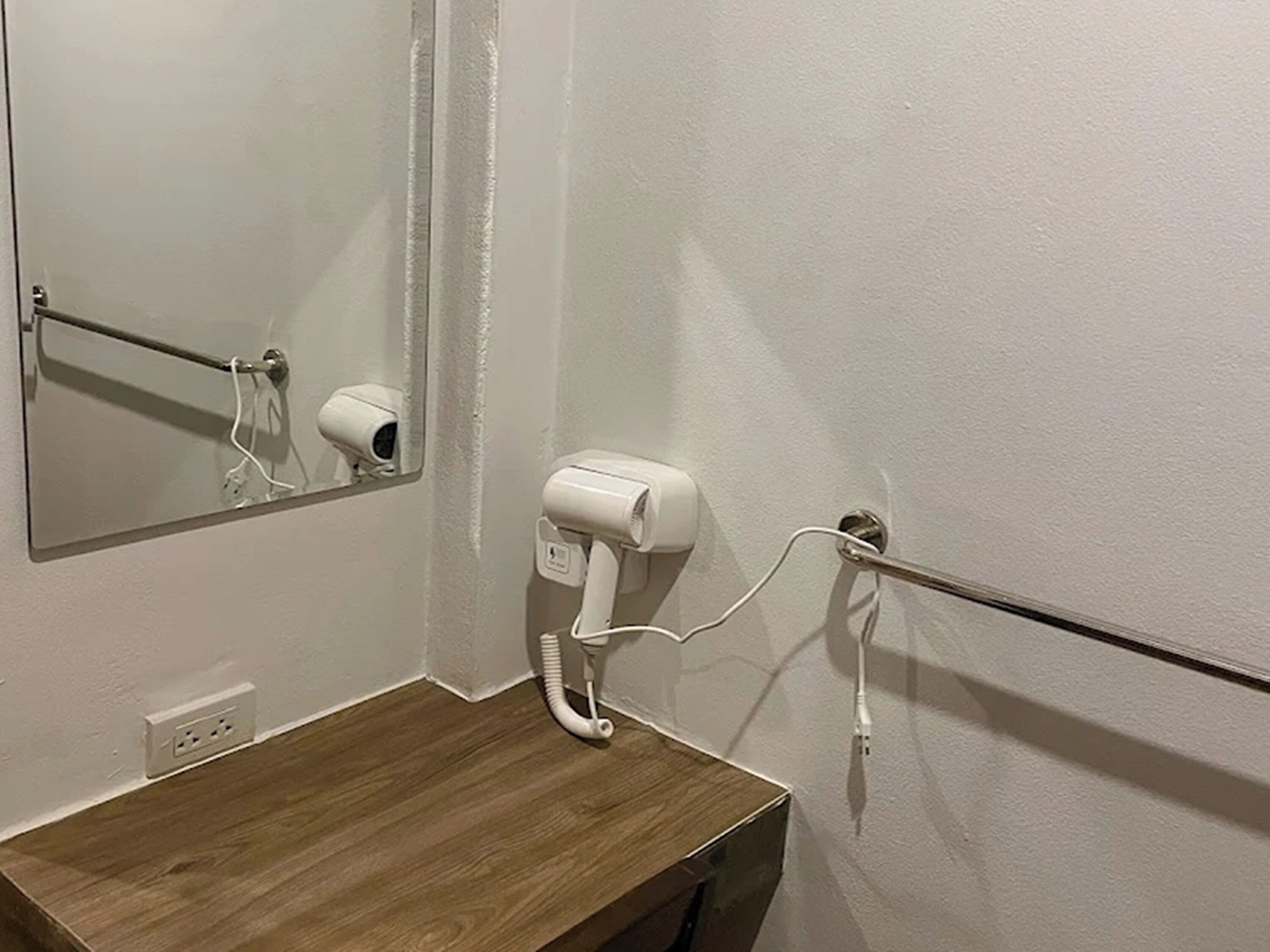 Un bagno con un mobile bagno in legno, uno specchio, un asciugacapelli e un porta asciugamani.