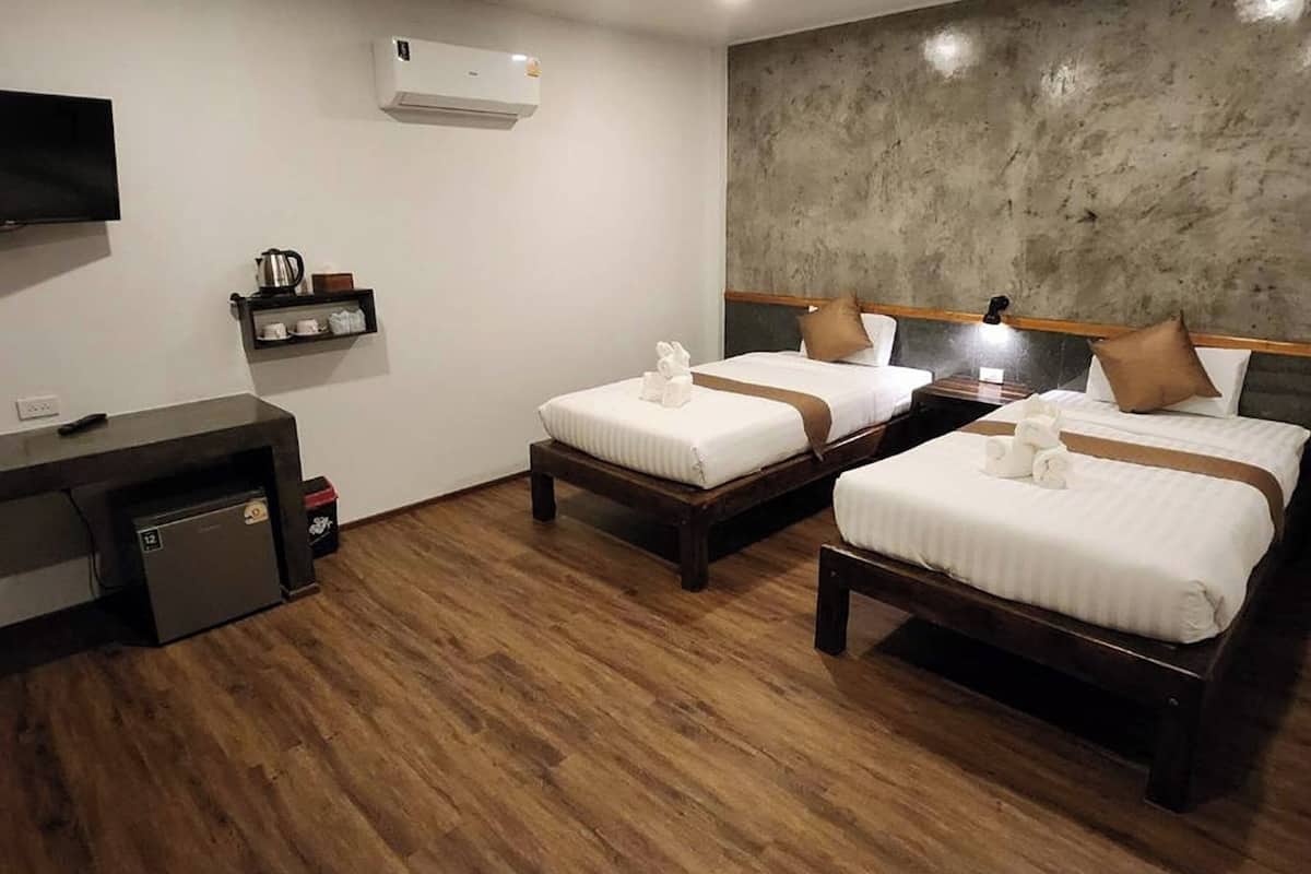 Habitación de hotel con dos camas, televisión, cafetera y una pequeña kitchenette.