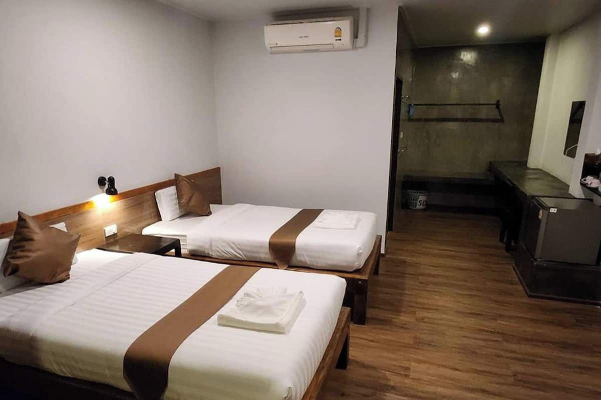Habitación de hotel con dos camas, un escritorio y una pequeña cocina.