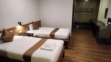 A hotel room with two beds, a desk, and a small kitchenette.
