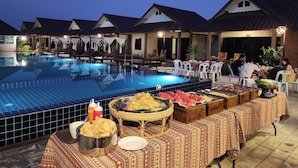 A poolside dining area with a buffet setup, lounge chairs, and a pool.