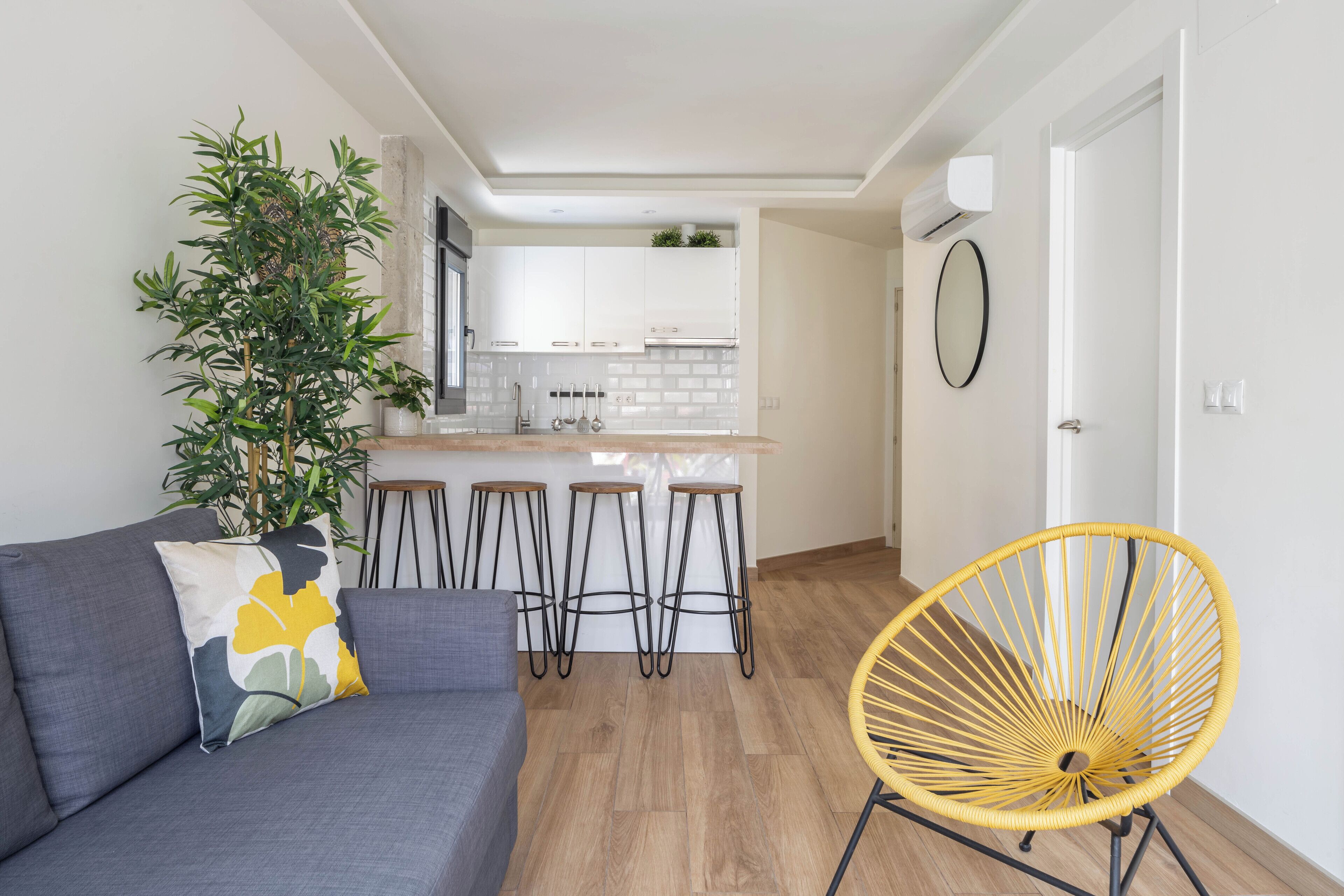 A modern kitchen with white cabinets, a central island, and a dining area with stools.