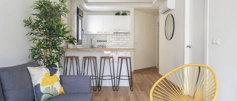 Una cocina moderna con armarios blancos, una isla central y una zona de comedor con taburetes.