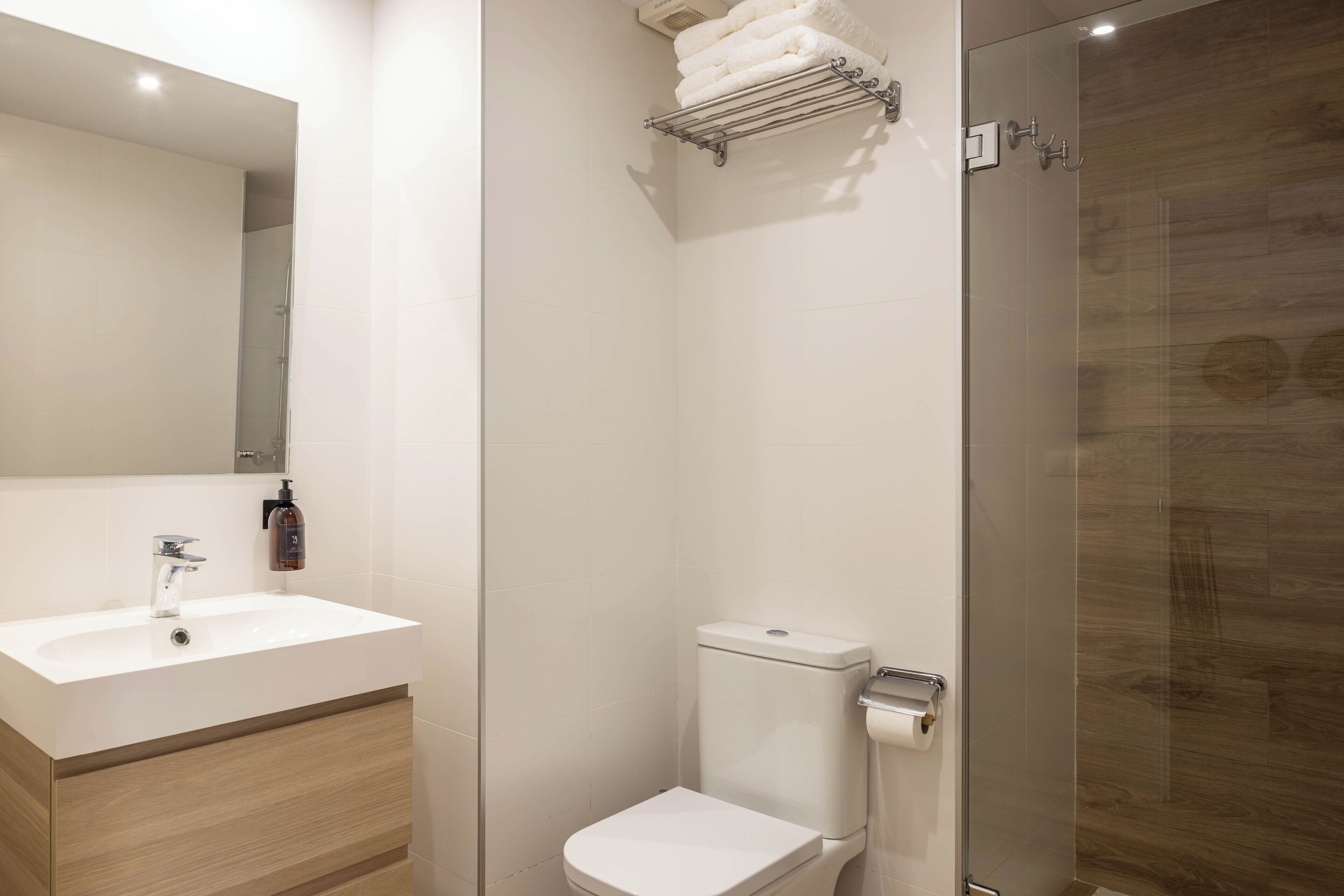 Une salle de bain moderne avec un lavabo blanc, des toilettes et une douche à parois de verre.