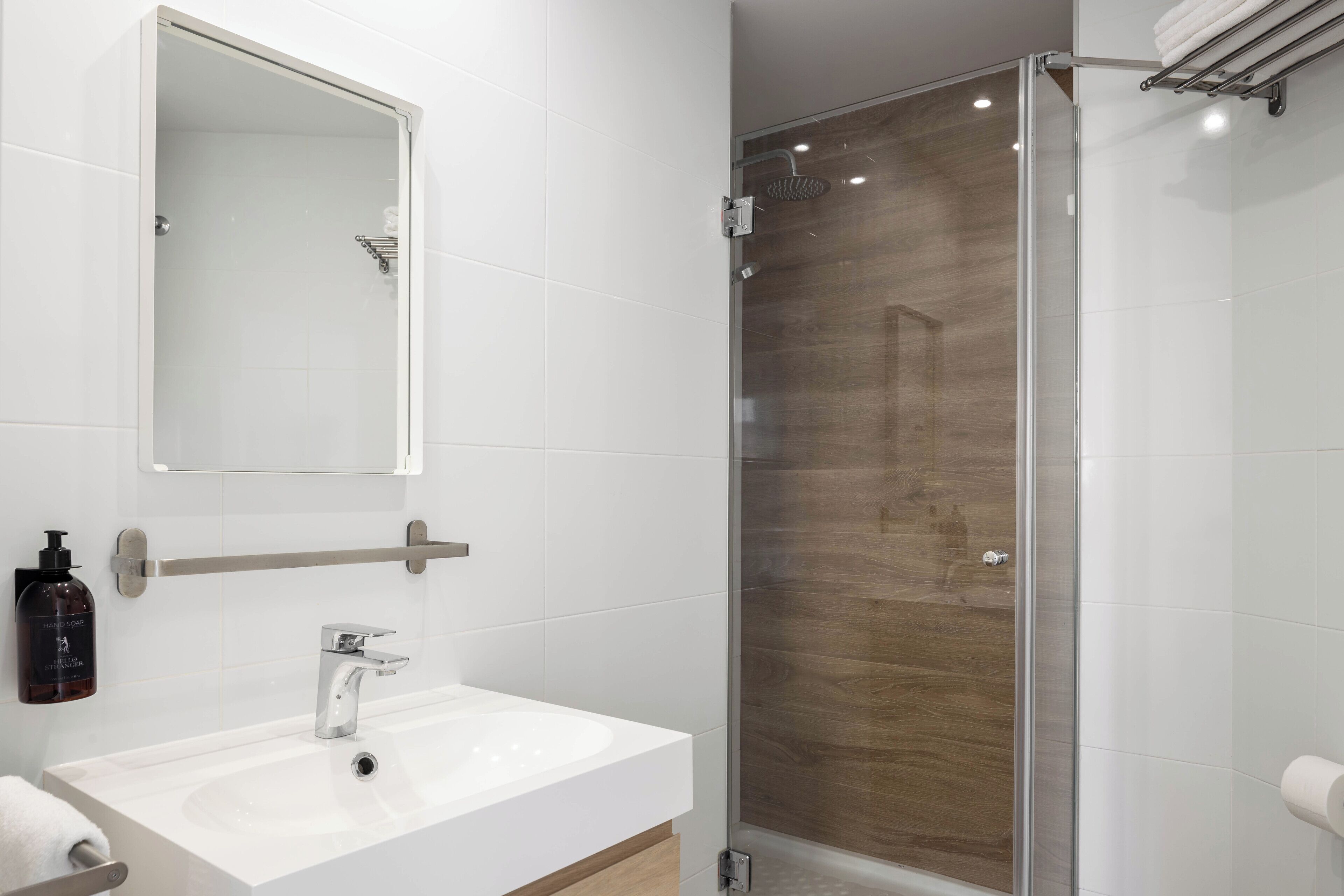 A modern bathroom with a white sink, a mirror, and a glass-enclosed shower.